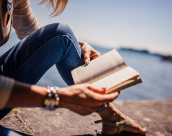 person reading outdoors by water